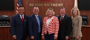 Image of the Orange County Board of Education, a group of three men and two women standing in front of an American flag and the California state flag.