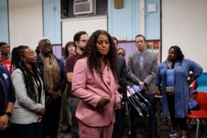 Chicago Teachers Union President Stacy Davis Gates in a pink suit, standing in front of a crowd at a press conference.